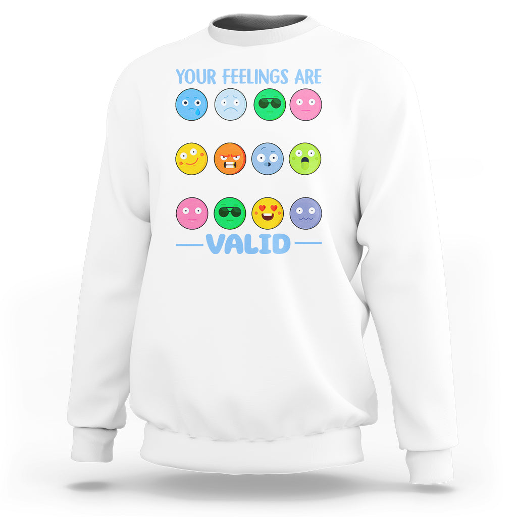 White sweatshirt with “YOUR FEELINGS ARE VALID” text and colorful emotion-face graphics.