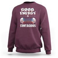 Maroon crewneck sweatshirt with “Good Energy Is Contagious” skull graphic on chest