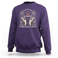 Purple crewneck sweatshirt with floral hands "Manifest Everything I Want" graphic