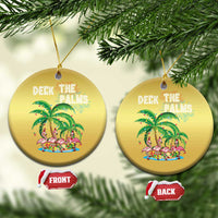 Two gold round “Deck the Palms” flamingo palm ornaments hanging from a tree