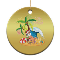 Gold circular Christmas ornament with Santa on beach scene, hanging from gold cord.