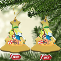 Gold bell-shaped ornament with Santa beach scene under palm trees, hanging on branches.