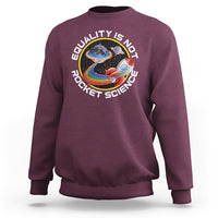Maroon crewneck sweatshirt with colorful rainbow planet graphic and “Equality is no Rocket Science” text