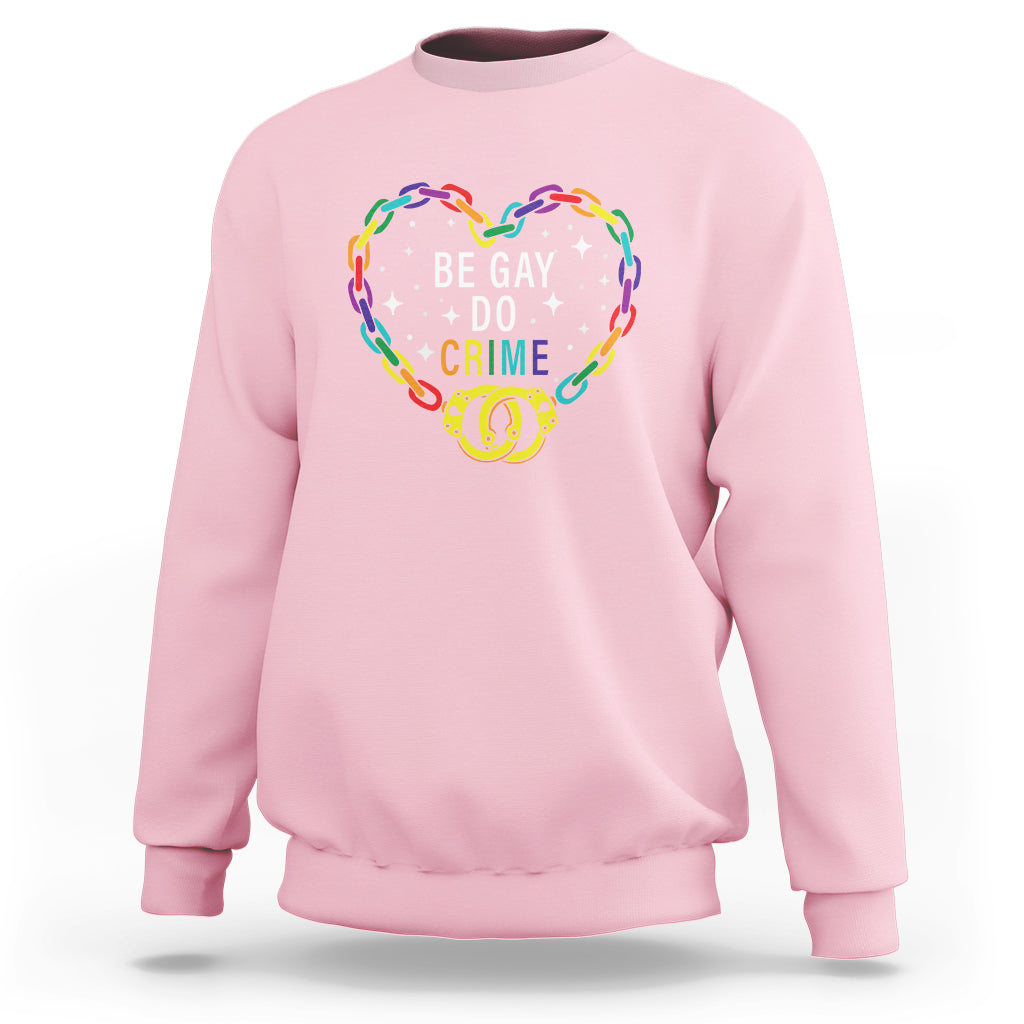 Light pink crewneck sweatshirt with rainbow heart graphic reading 'BE GAY DO CRIME'