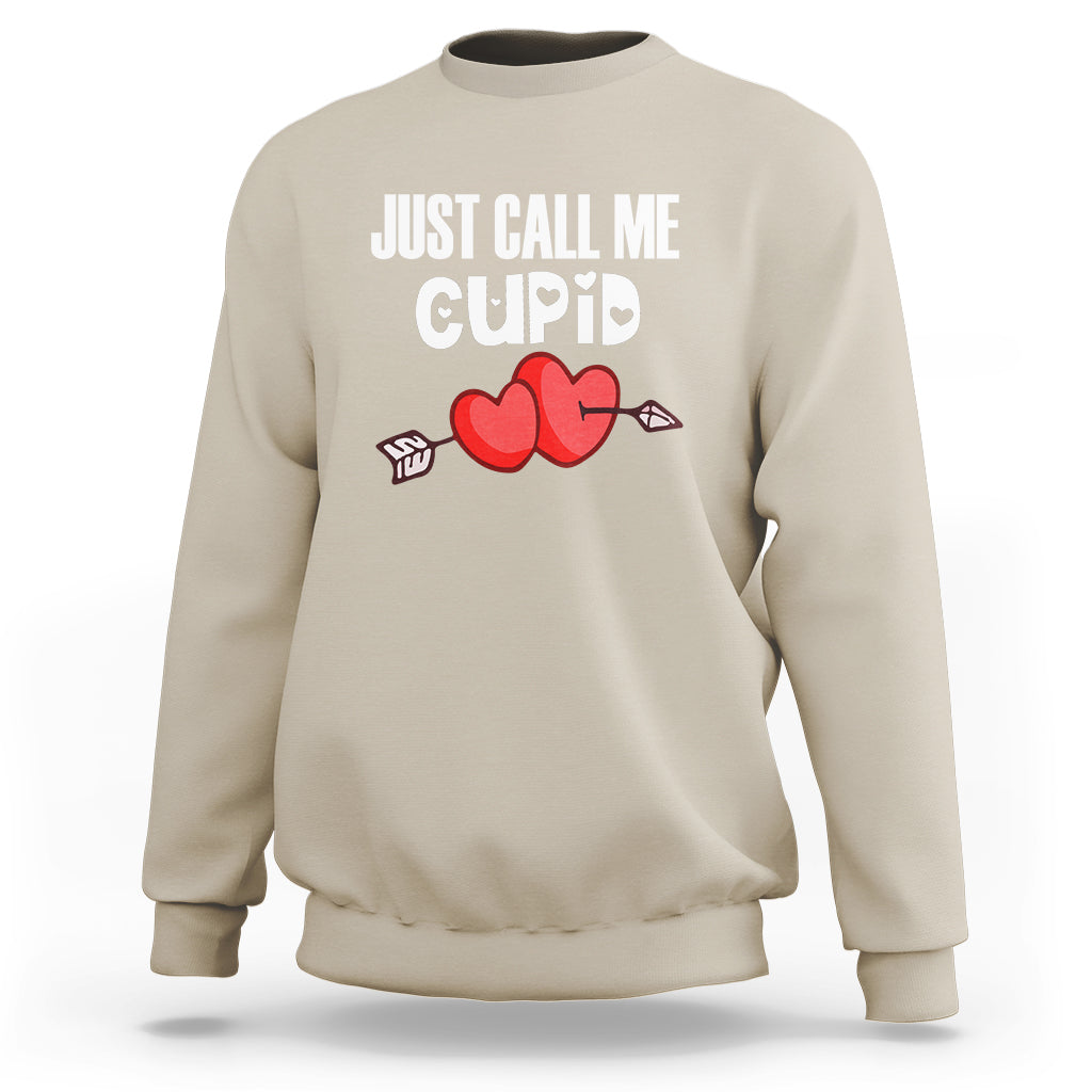 Sand crewneck sweatshirt with “JUST CALL ME CUPID” text and red heart-arrow graphic