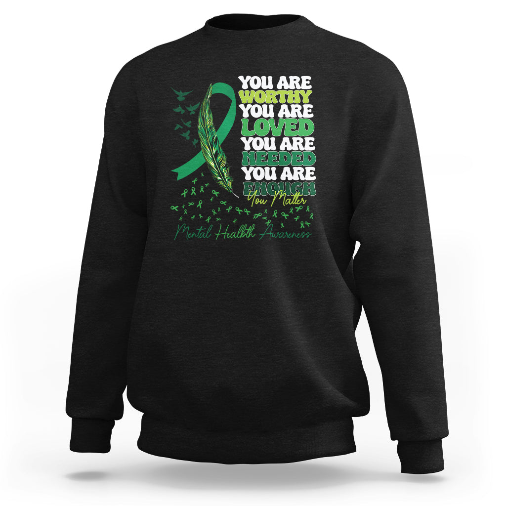 Black crewneck sweatshirt with front ribbon-and-leaves motivational text graphic.