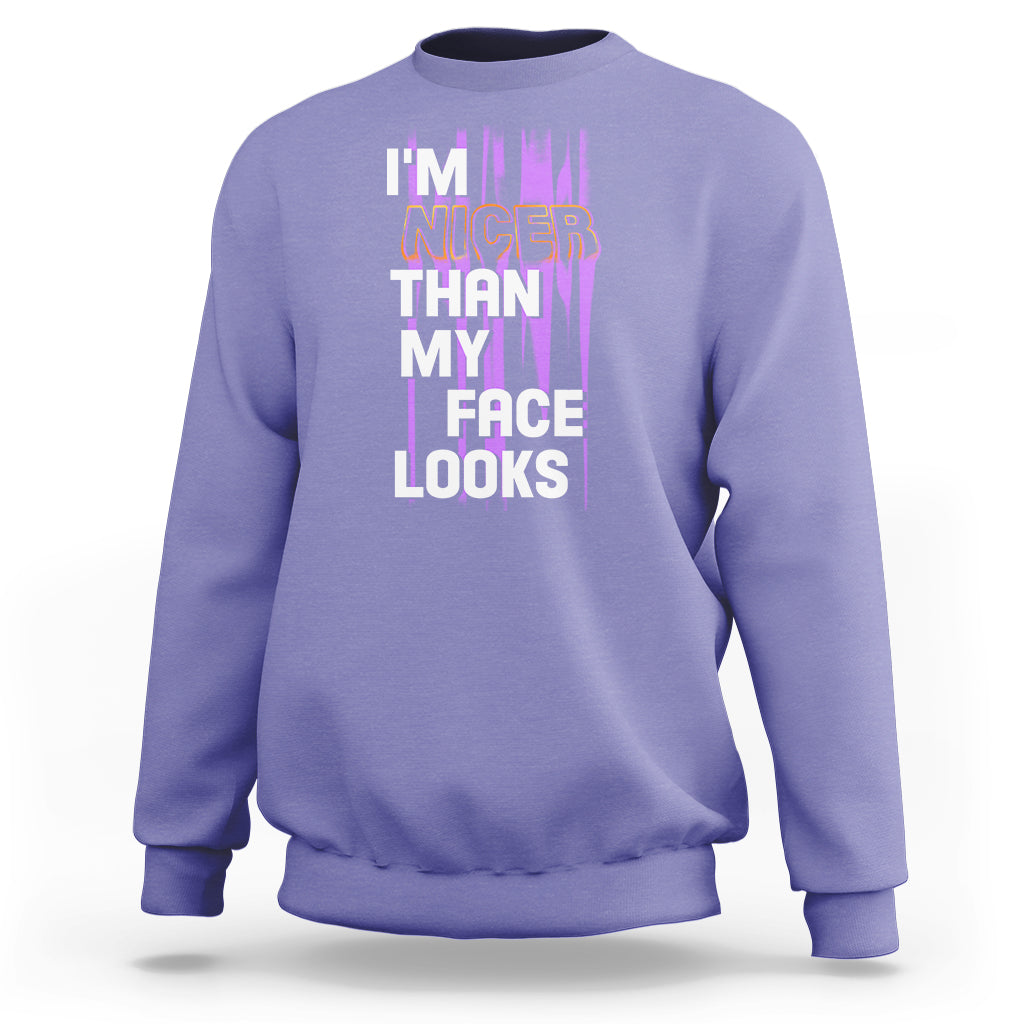 Violet crewneck sweatshirt with front graphic text: “I’m nicer than my face looks”