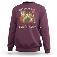 Maroon crewneck sweatshirt with graphic text 'OFTEN ALONE' and 'RARELY LONELY'.