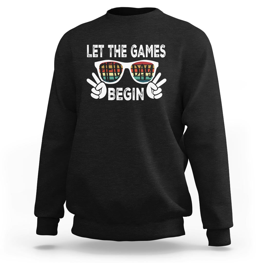 Black sweatshirt with “LET THE GAMES BEGIN” graphic and sunglasses hands