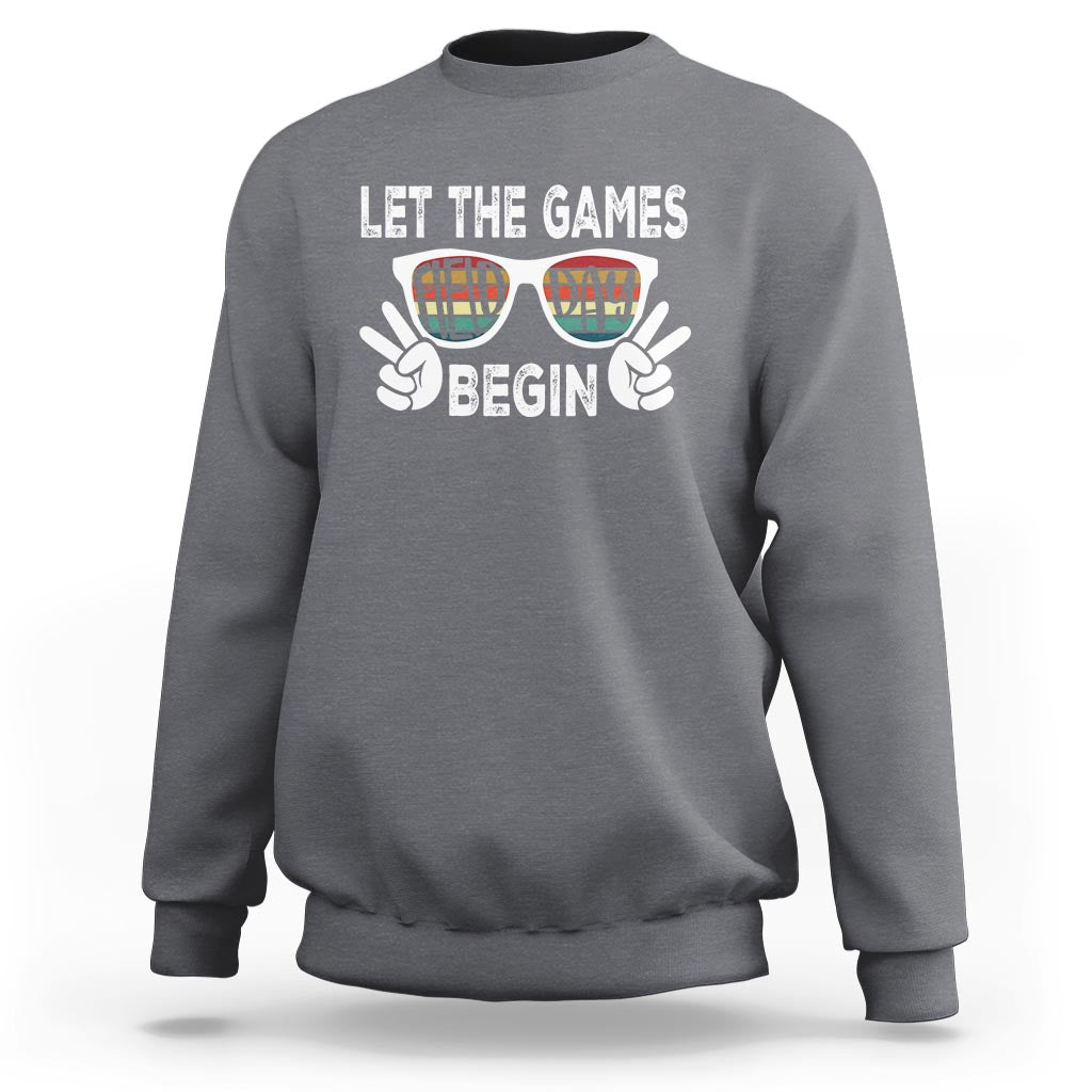 Heather gray sweatshirt with “LET THE GAMES BEGIN” graphic and sunglasses hands