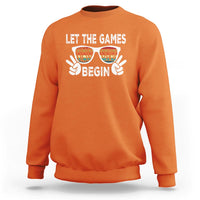 Orange sweatshirt with “LET THE GAMES BEGIN” graphic and sunglasses hands