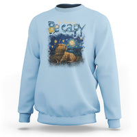 Light blue crewneck sweatshirt with colorful capybara night graphic on the front