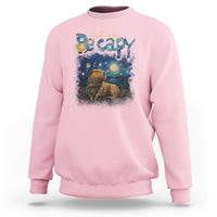 Light pink crewneck sweatshirt with colorful capybara night graphic on the front