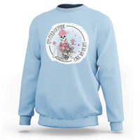 Light blue crewneck sweatshirt with circular skeleton and rose floral graphic on chest.