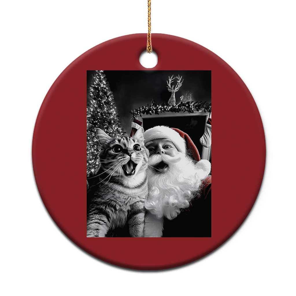Red circular Christmas ornament with a grayscale cat-and-Santa photo, hanging on a gold cord.