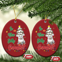 Two red round cat Christmas ornaments hanging on evergreen branches with gold hooks.