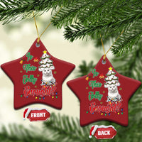 Two red star-shaped cat Christmas ornaments hanging on evergreen branches.