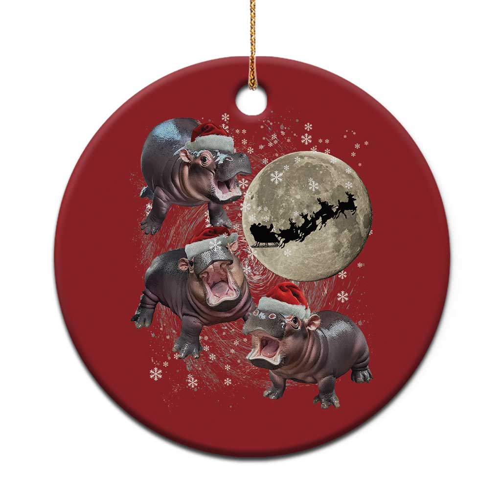 Red round Christmas ornament with cartoon baby hippos, Santa, and a moon graphic; gold loop