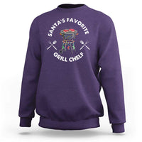 Purple crewneck sweatshirt with BBQ chef graphic and “Santa’s Favorite Grill Chef” text.