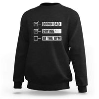 Black crewneck sweatshirt with “DOWN BAD,” “CRYING,” “AT THE GYM” text graphic on back