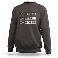 Dark chocolate crewneck sweatshirt with “DOWN BAD,” “CRYING,” “AT THE GYM” text graphic on back