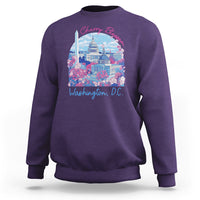 Purple crewneck sweatshirt with colorful cherry blossom city graphic on chest