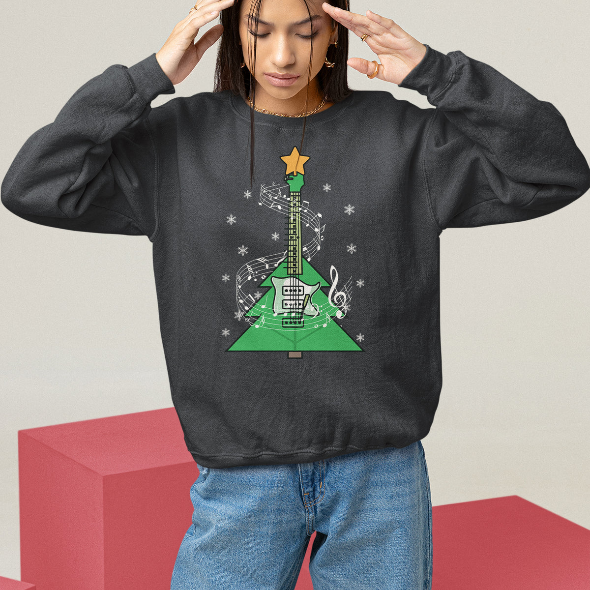 Charcoal crewneck sweatshirt on model with hands raised; green guitar-themed Christmas tree graphic