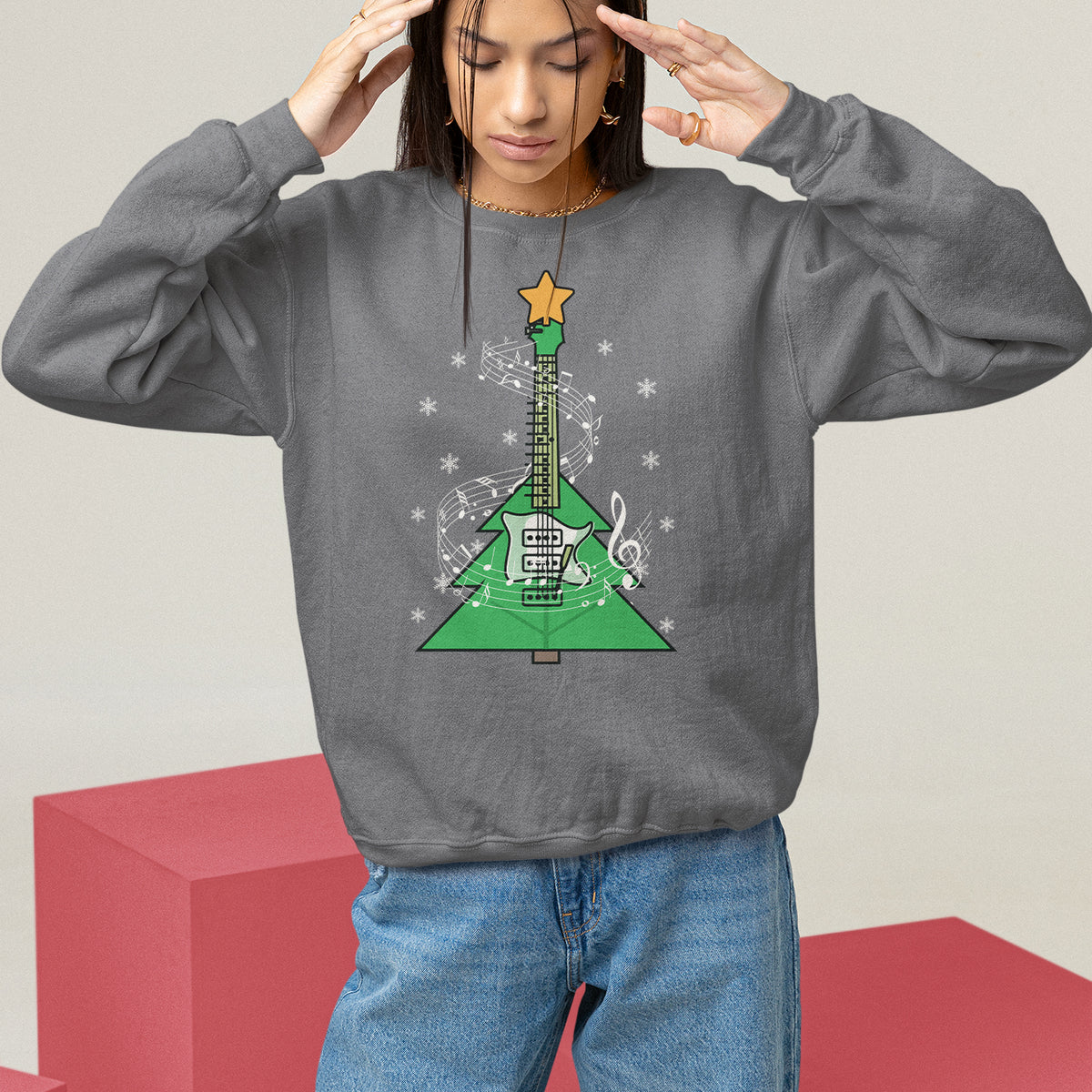 Charcoal crewneck sweatshirt on model with hands raised; green Christmas tree guitar note graphic