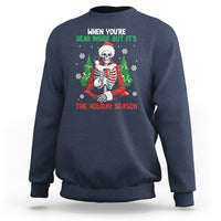 Navy crewneck sweatshirt with cartoon skeleton in Santa hat and "THE HOLIDAY SEASON" print
