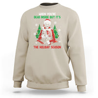 Sand color crewneck sweatshirt with cartoon skeleton in Santa hat and "THE HOLIDAY SEASON" print