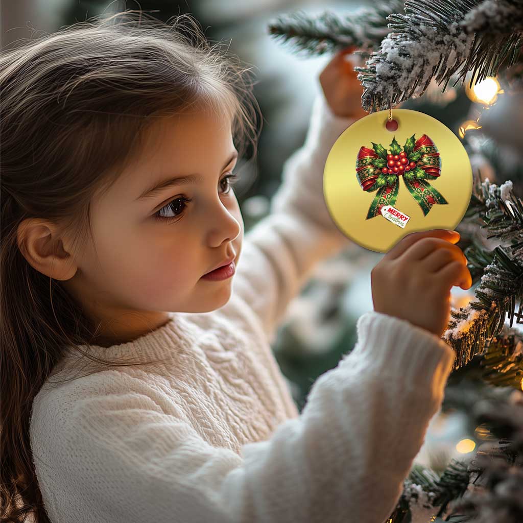 Gold Christmas bow ornament on a tree, featuring red holly ribbons and “Merry Christmas”