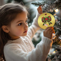 Gold Christmas bow ornament on a tree, featuring red holly ribbons and “Merry Christmas”
