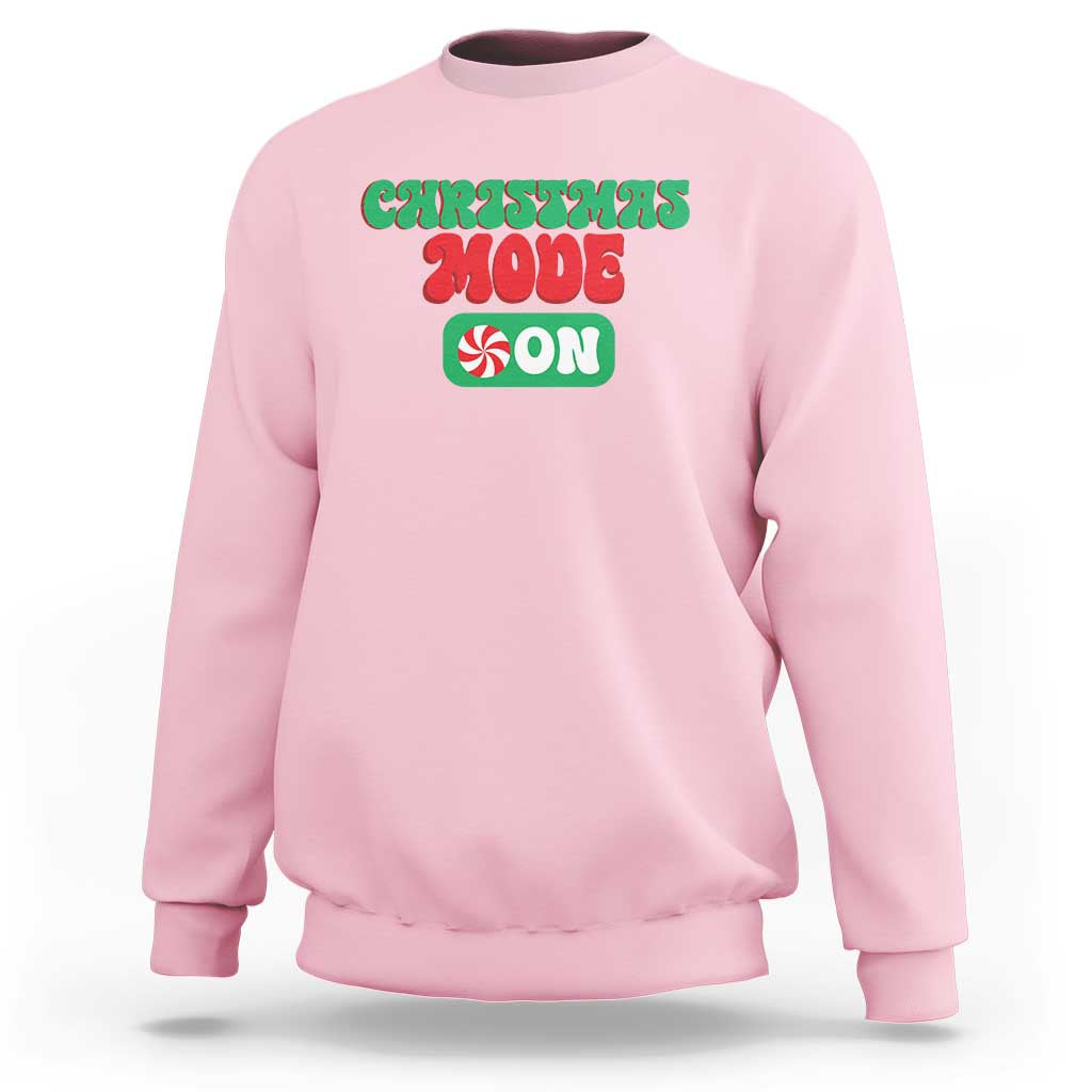 Light pink crewneck sweatshirt with front holiday graphic text, long sleeves