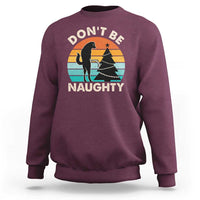 Maroon crewneck sweatshirt with “DON’T BE NAUGHTY” graphic and dog silhouette