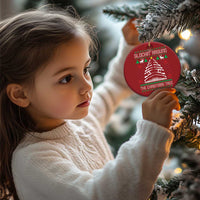 Red round Christmas ornament hanging on a Christmas tree branch with tree graphic