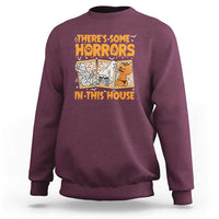 Funny Halloween sweatshirt in maroon, with “There’s Some Horrors In This House” graphic.
