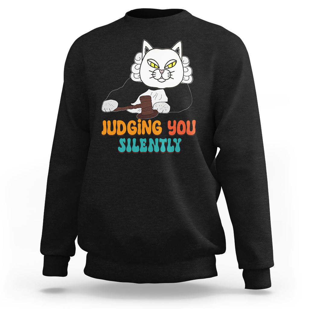 Black sweatshirt with cat graphic and “JUDGING YOU” “SILENTLY” text on front.