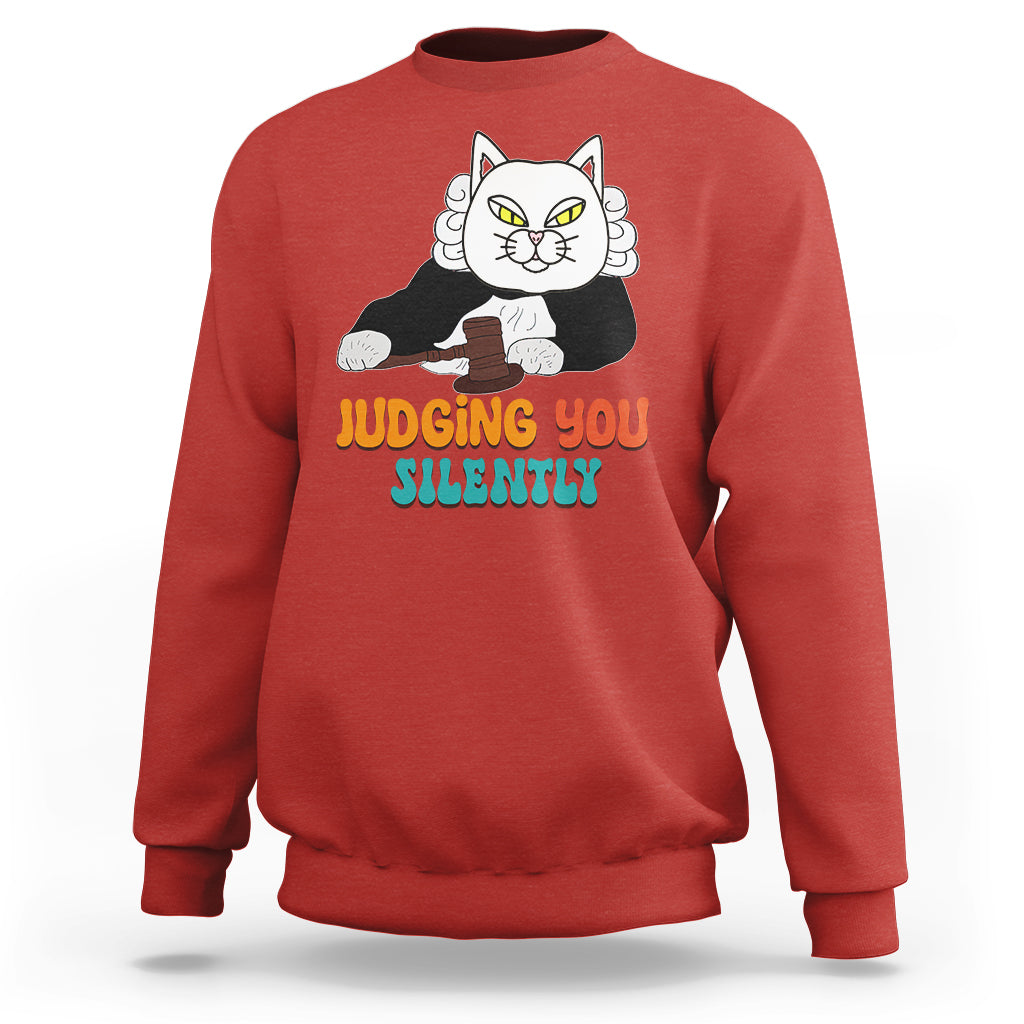 Red sweatshirt with cat graphic and “JUDGING YOU” “SILENTLY” text on front.