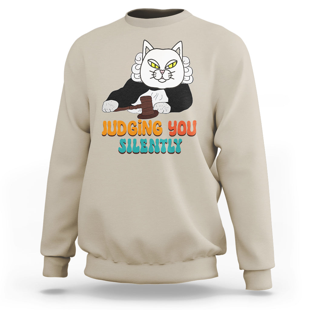 Sand/beige sweatshirt with cat graphic and “JUDGING YOU” “SILENTLY” text on front.