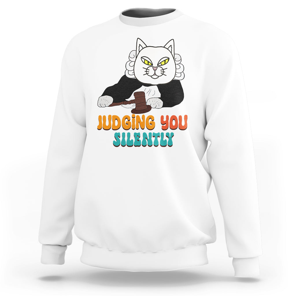 White sweatshirt with cat graphic and “JUDGING YOU” “SILENTLY” text on front.