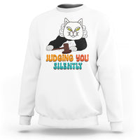 White sweatshirt with cat graphic and “JUDGING YOU” “SILENTLY” text on front.