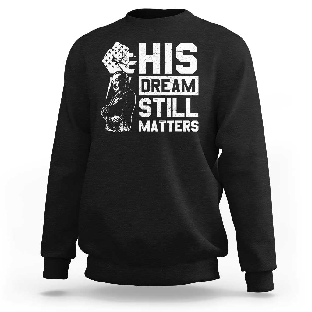 Black crewneck sweatshirt with white "HIS DREAM STILL MATTERS" graphic front.