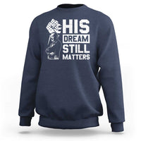 Navy crewneck sweatshirt with white "HIS DREAM STILL MATTERS" graphic front.