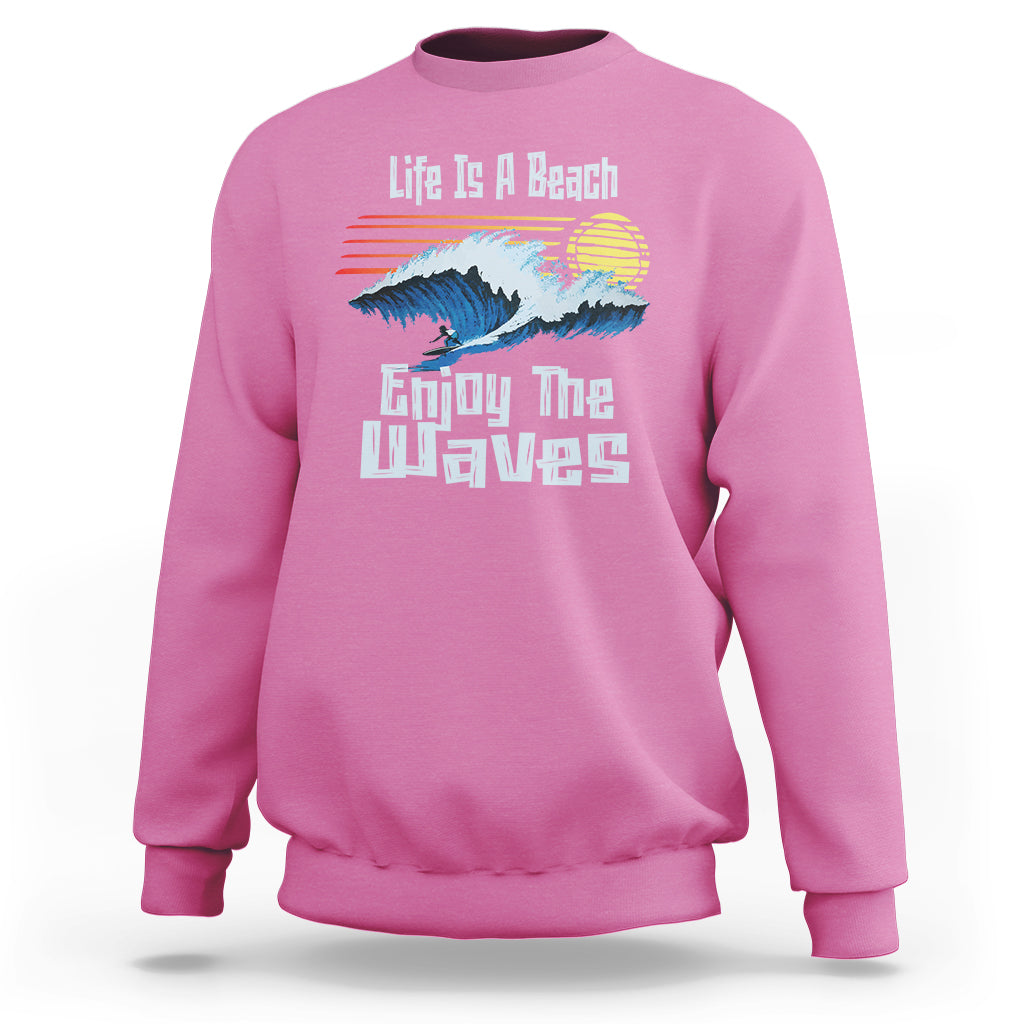 Pink crewneck sweatshirt with beach wave graphic and “Enjoy The Waves” text