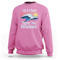 Pink crewneck sweatshirt with beach wave graphic and “Enjoy The Waves” text