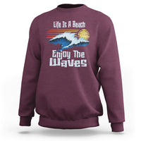 Maroon crewneck sweatshirt with beach wave graphic and “Enjoy The Waves” text