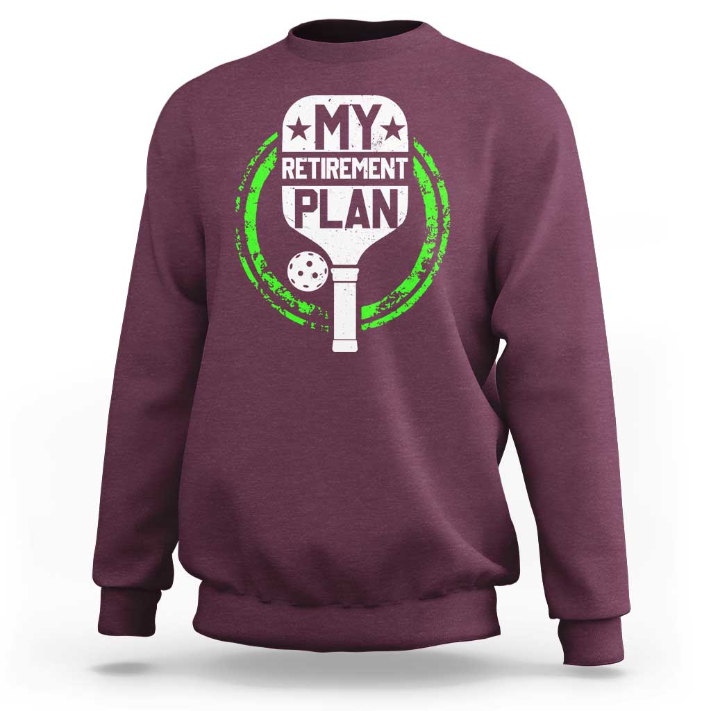 Maroon crewneck sweatshirt with green pickleball retirement graphic on chest.