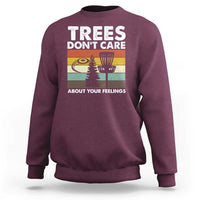 Maroon crewneck sweatshirt with “Trees don’t care” graphic and trees scene.