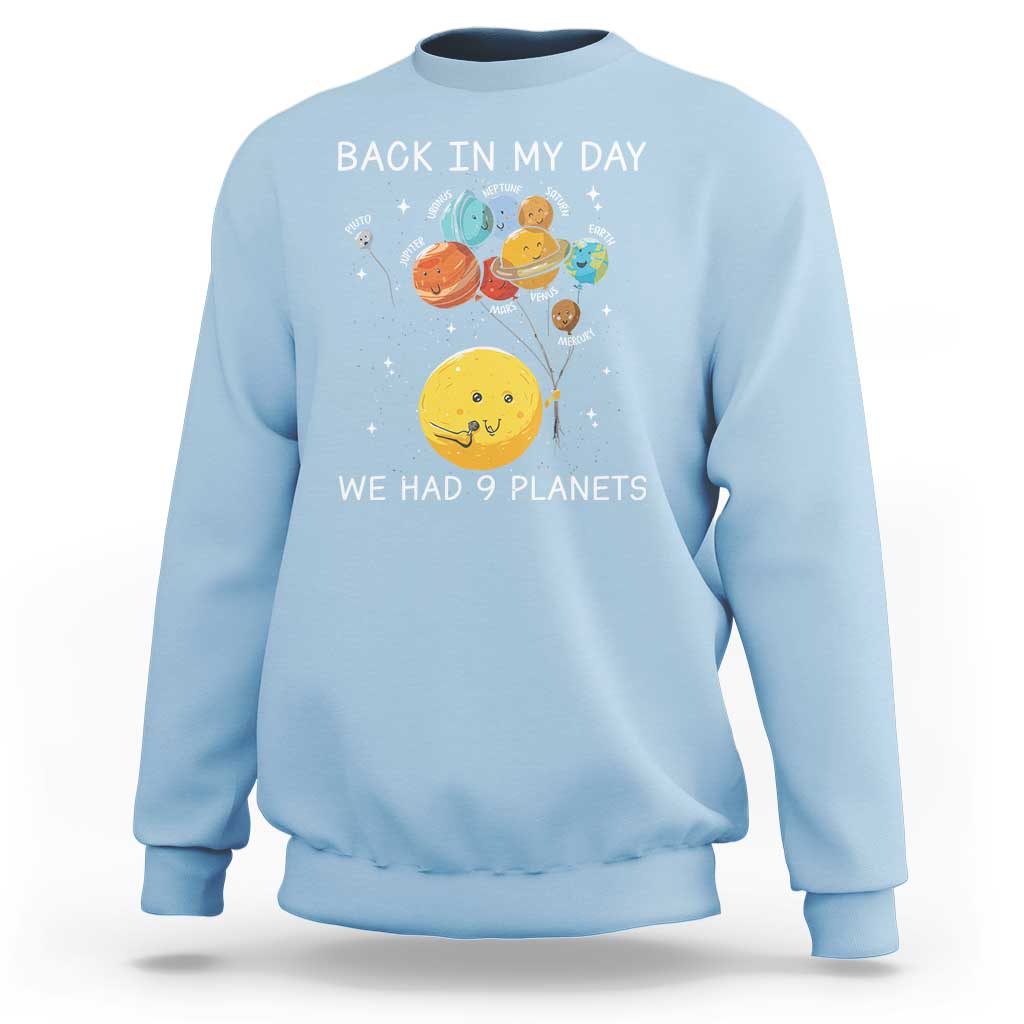 Light blue crewneck sweatshirt with space planets graphic and 'We Had 9 Planets' wording.