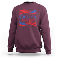 Maroon crewneck sweatshirt with patriotic “Creed '24” graphic and wavy flag print